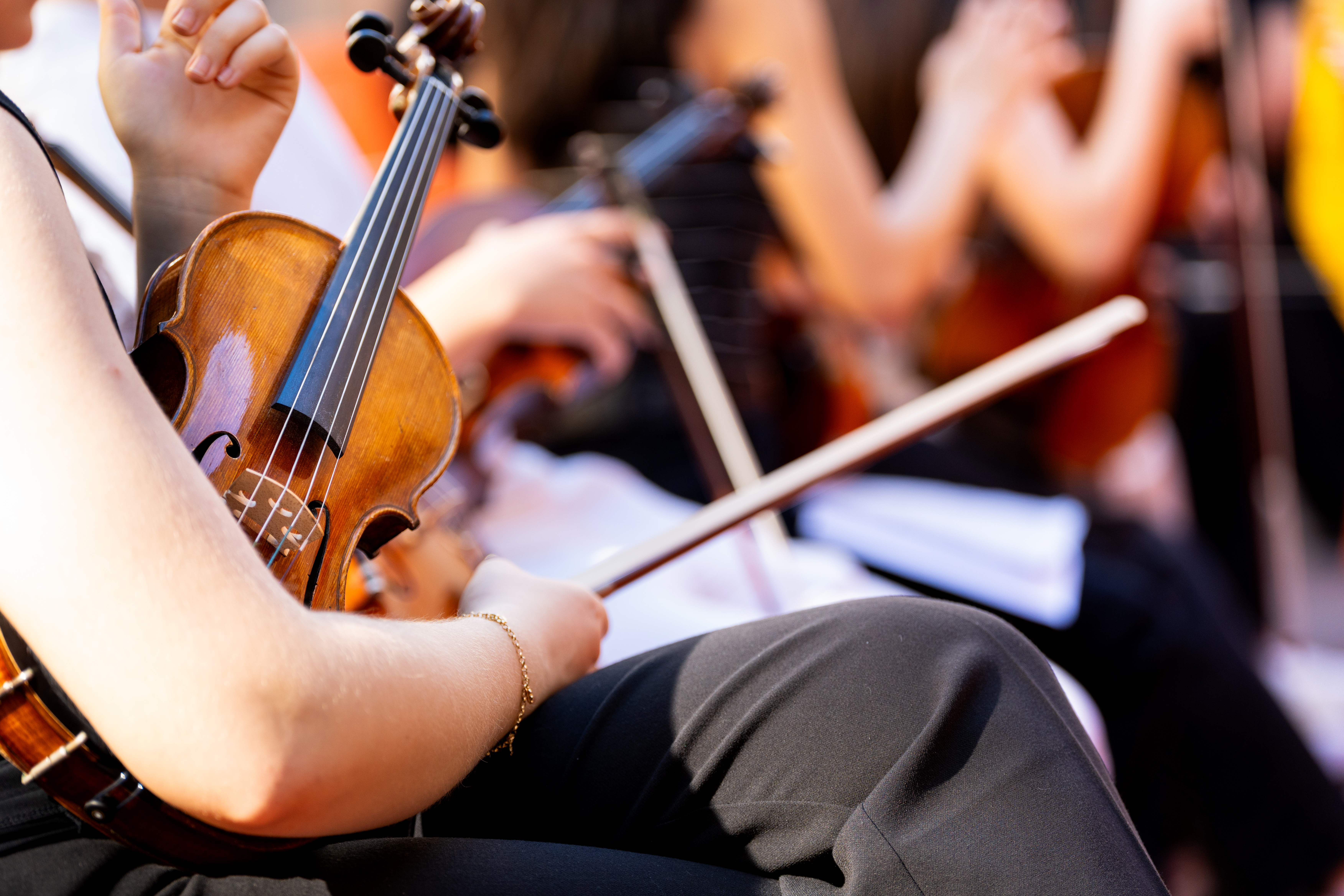 Musician playing violin in an orchestra, performing classical music for a captivated audience